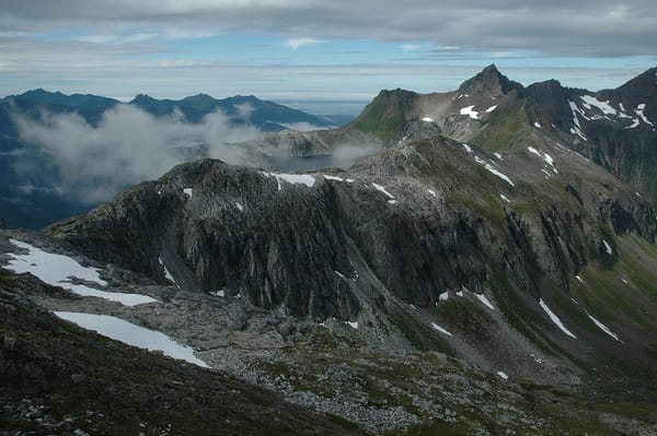 Looking out from a high mountain ridge toward a mountain like, with higher peaks all around it.